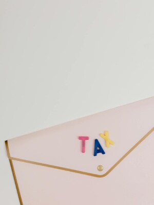 Pink envelope with TAX letters arranged on top, symbolizing tax-related themes.